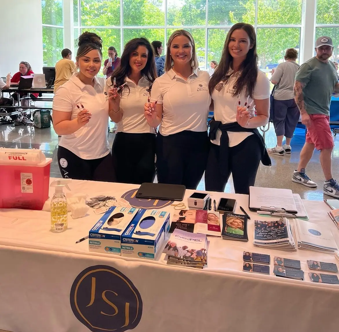 a group of women standing in front of a table with a table with items