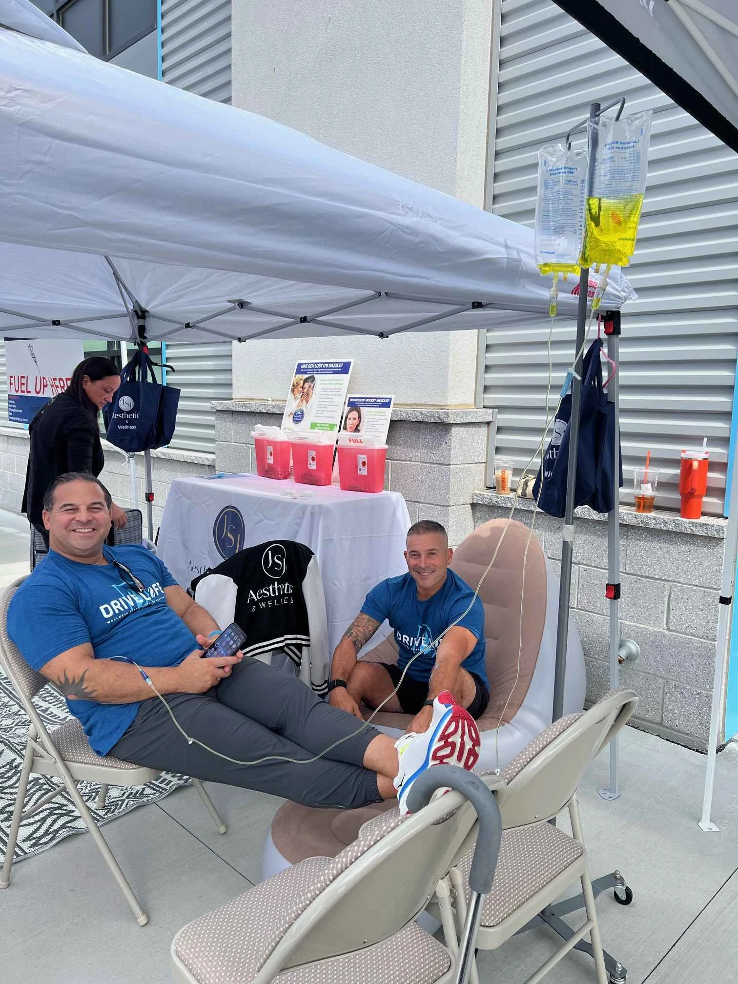 two men sitting in chairs under a tent