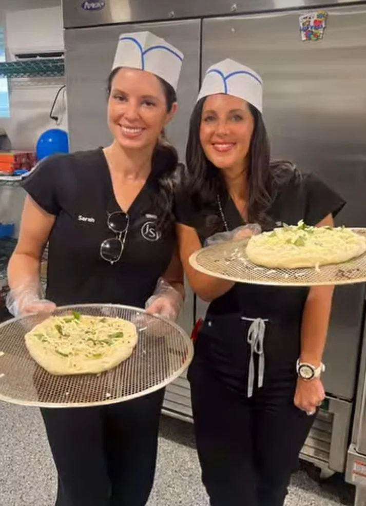 a couple of women holding pizzas