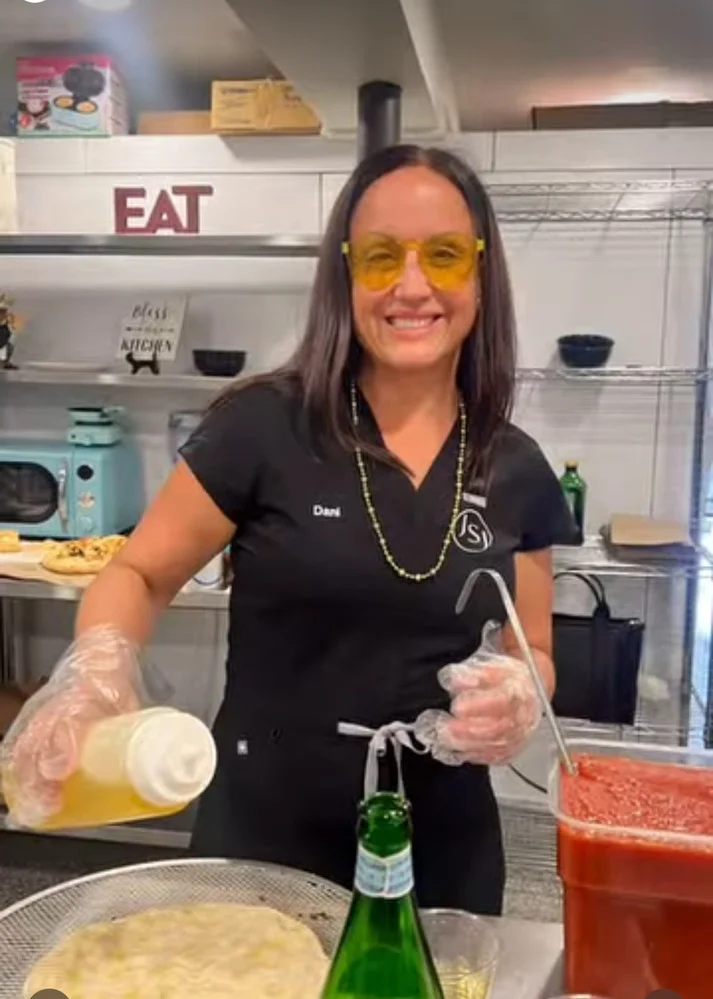 a woman wearing yellow glasses and gloves holding a bottle of juice