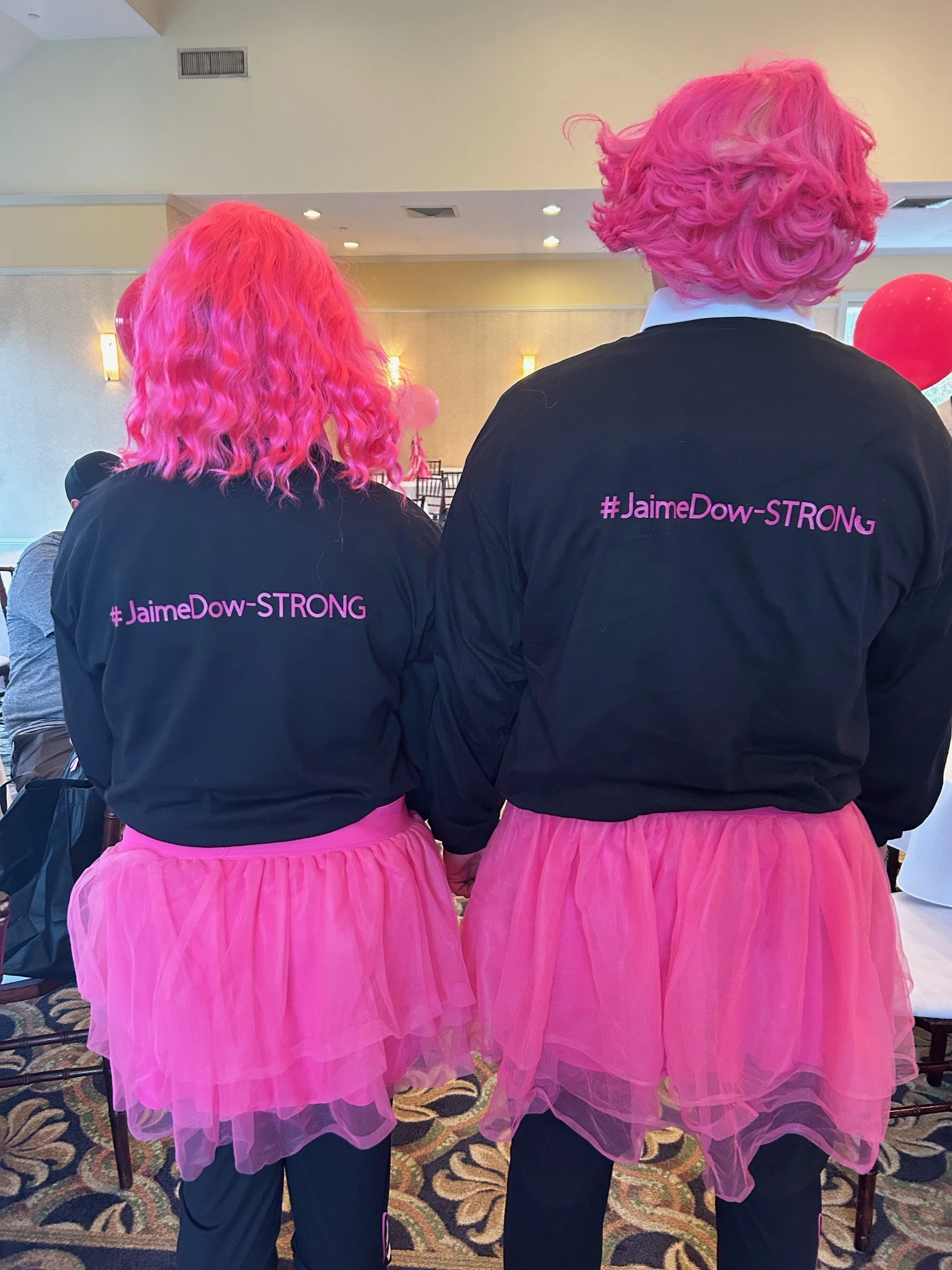 two people wearing pink wigs and matching shirts