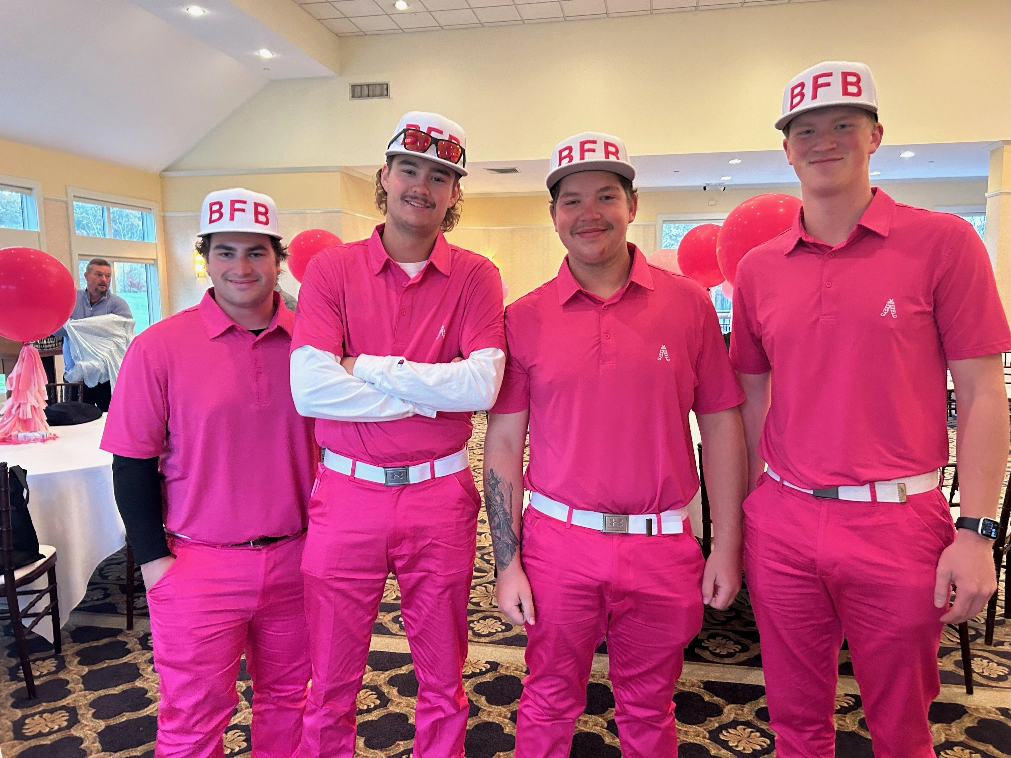 a group of men wearing pink shirts and hats