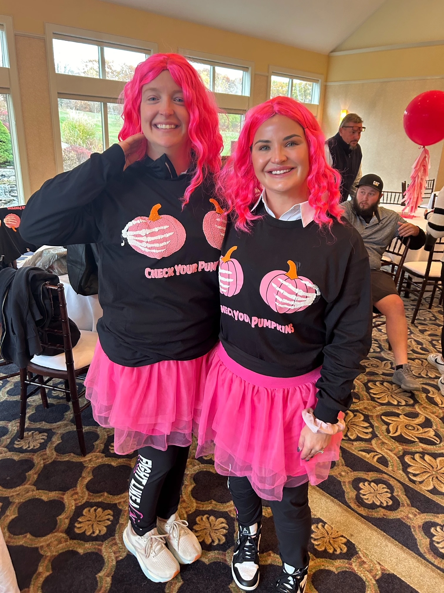 two women wearing pink wigs and matching shirts