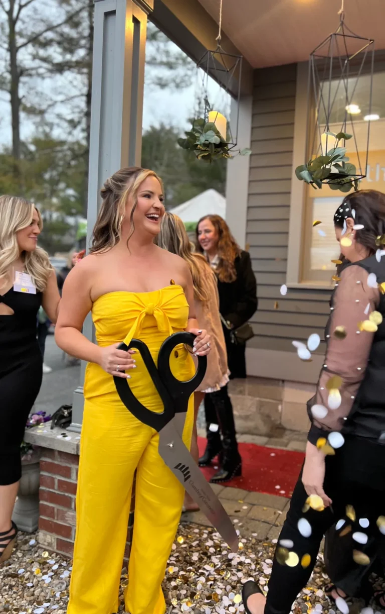 a woman in a yellow jumpsuit holding a large pair of scissors